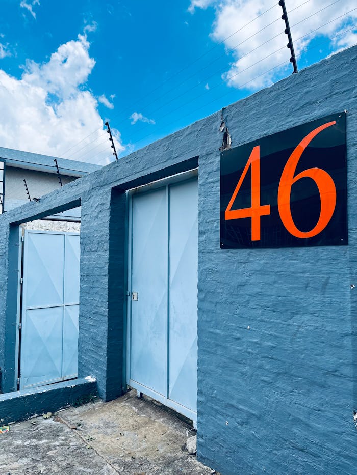 Blue wall and gate with bold orange number 46 under a vibrant sky.