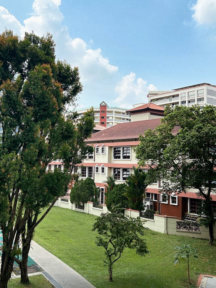 A vibrant urban residential complex surrounded by lush greenery under a bright blue sky.